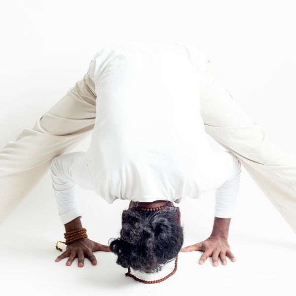 Person doing a flowing yoga movement in a minimalist dark room.