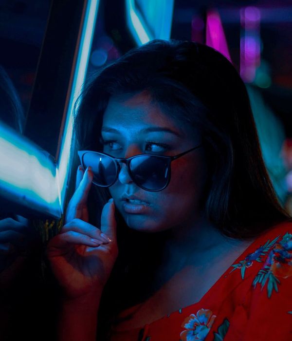 Woman in a calm yoga pose against a dark background with cyan glow.